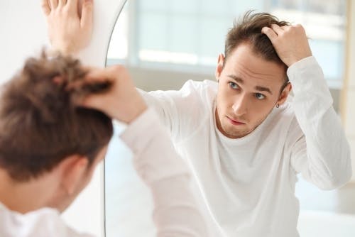 man checking hair in mirror